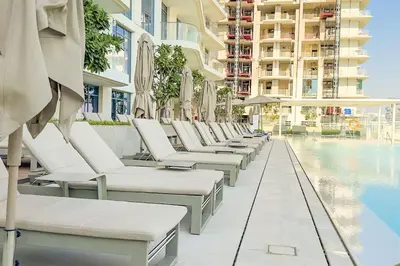 a row of chaise lounge chairs next to a swimming pool at Stunning Palm View 1BR Apartment in Dubai Harbour in Dubai