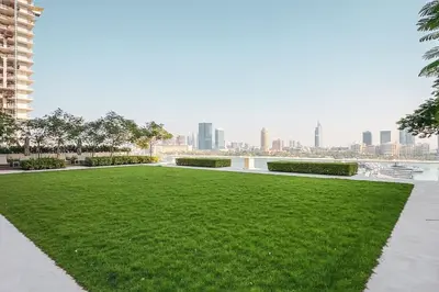 a park with green grass and a city in the background at Stunning Palm View 1BR Apartment in Dubai Harbour in Dubai