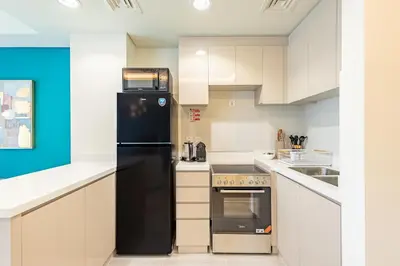 a kitchen with white cabinets and a black refrigerator at Luxury 3BR 2storey Villa with Garden in Damac Hills in Dubai