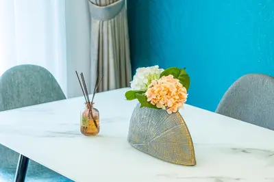 a white table with a vase with flowers on it at Luxury 3BR 2storey Villa with Garden in Damac Hills in Dubai