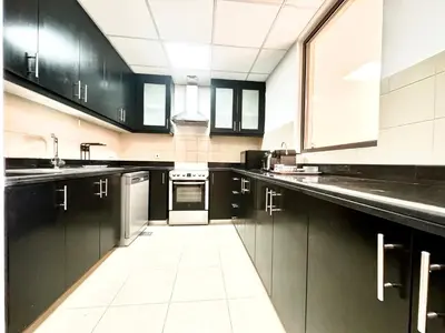 a kitchen with black cabinets and a white tile floor at Stylish beachside apartment 3 beds in JBR in Dubai