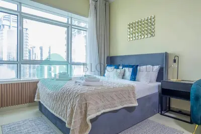 a bedroom with a bed and a large window at Bloomfields Deluxe Stu Jlt Near Metro in Dubai
