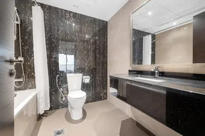 a bathroom with a toilet and a sink and a mirror at Close to Downtown - New 1 bedroom with parking in Dubai