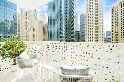 a balcony with tables and chairs and a city skyline at LUX The JBR Garden View Suite in Dubai