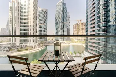 a table with two chairs and a view of a city at Amazing lake skyline view cozy apartment in Dubai