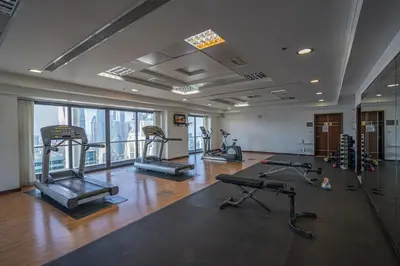 a gym with several treadmills and machines in a room at Amazing lake skyline view cozy apartment in Dubai