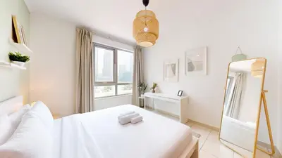 a white bedroom with a white bed and a mirror at The Residences II - One Bed with Burj Khalifa View in Dubai