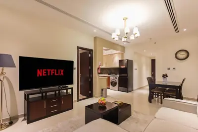 a living room with a tv on a wall at Spacious 1BR - Elite Downtown Residence - Short Walk to Burj & Dubai Mall in Dubai