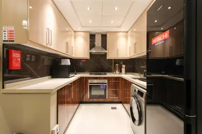 a kitchen with wooden cabinets and a washer and dryer at Spacious 1BR - Elite Downtown Residence - Short Walk to Burj & Dubai Mall in Dubai