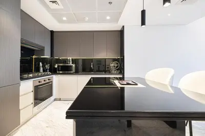 a kitchen with a black counter and white cabinets at Upscale 2BR with Private Terrace & Pool View in Dubai