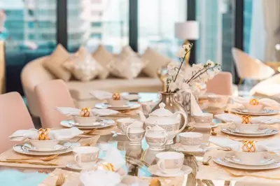 a table with plates and cups and a vase with flowers at Elite Royal Apartment - Sky Series - Panoramic Burj Khalifa, Skyline & Fountain View - Admiral in Dubai