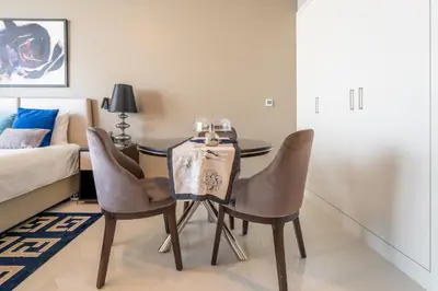 a dining room with a table and chairs and a bed at Stylish Studio with Pool View & Free Parking in Dubai