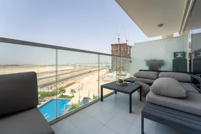 a living room with a balcony with a view of the beach at Stylish Studio with Pool View & Free Parking in Dubai