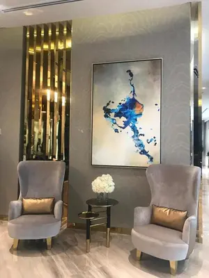 two chairs and a table in a lobby with a painting at Damac Majestine VIP - Manzar Holiday Homes in Dubai