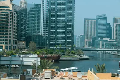 a river with a boat in a city with tall buildings at Classic Charm a Studio with Iconic Marina Views in Dubai