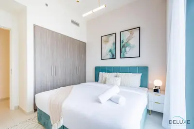 a bedroom with a large white bed with a blue headboard at Captivating 2BR Apartment in Park Ridge Tower C , Dubai Hills Estate by Deluxe Holiday Homes in Dubai