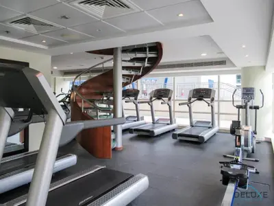 a gym with several treadmills and a spiral staircase at Stylish 1BR Apartment in Al Sahab 2, Dubai Marina by Deluxe Holiday Homes in Dubai