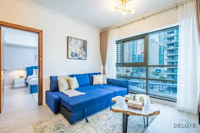 a blue couch in a living room with a window at Stylish 1BR Apartment in Al Sahab 2, Dubai Marina by Deluxe Holiday Homes in Dubai