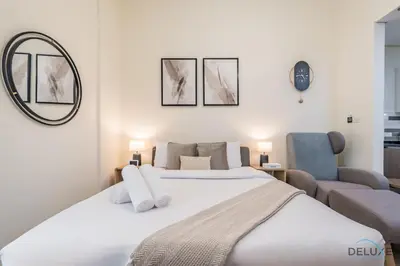 a bedroom with a large white bed and a chair at Stunning Studio Apartment in Azizi Star , Jebel Ali by Deluxe Holiday Homes in Dubai
