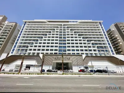 a large white building with cars parked in front of it at Stunning Studio Apartment in Azizi Star , Jebel Ali by Deluxe Holiday Homes in Dubai