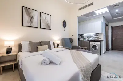 a bedroom with a large white bed and a kitchen at Stunning Studio Apartment in Azizi Star , Jebel Ali by Deluxe Holiday Homes in Dubai