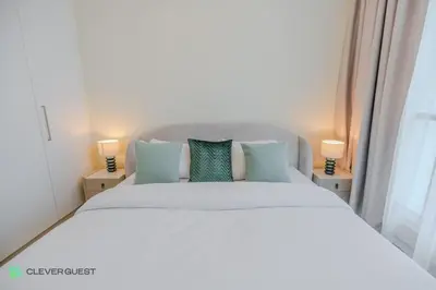 a bedroom with a large white bed with two lamps at Clever Guest 027 Acacia A in Dubai