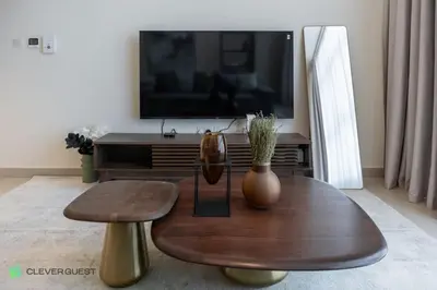 a living room with a wooden coffee table and a tv at Clever Guest 027 Acacia A in Dubai