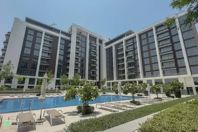 a large apartment building with a pool and chairs at Clever Guest 027 Acacia A in Dubai