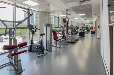 a gym with rows of treadmills and machines at Clever Guest 027 Acacia A in Dubai