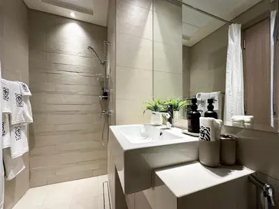 a white bathroom with a sink and a shower at Trophy Modern Marvel Cozy Studio with Smart Features in Azizi Riviera in Dubai
