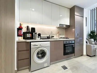 a kitchen with a washing machine and a stove at Trophy Modern Marvel Cozy Studio with Smart Features in Azizi Riviera in Dubai