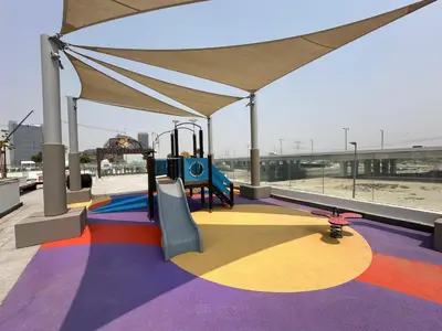 a playground with a slide and a swing at Trophy Modern Marvel Cozy Studio with Smart Features in Azizi Riviera in Dubai