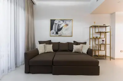 a living room with a brown couch in a room at Dubai Creek - Bright & Beautiful 1BR in The Cove in Dubai