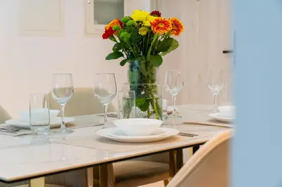 a table with glasses and a vase of flowers on it at Dubai Creek - Bright & Beautiful 1BR in The Cove in Dubai