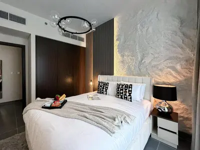 a bedroom with a large white bed and a wall at Trophy - Ultra Luxury Suite with Fireplace in Dubai