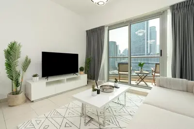 a white living room with a flat screen tv at Gala Guests - Stunning Front-Row Marina Views at The Point in Dubai