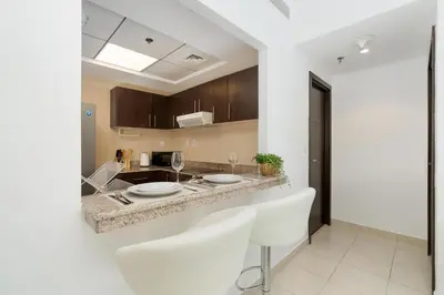 a kitchen with white chairs and a counter top at Gala Guests - Stunning Front-Row Marina Views at The Point in Dubai