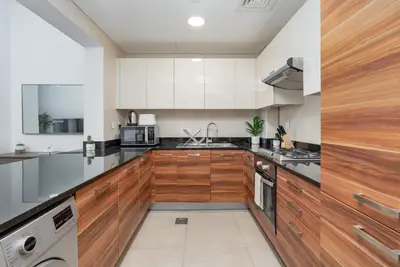 a kitchen with wooden cabinets and a sink at Gala Guests - Deluxe Sparkle Residences Dubai Marina in Dubai