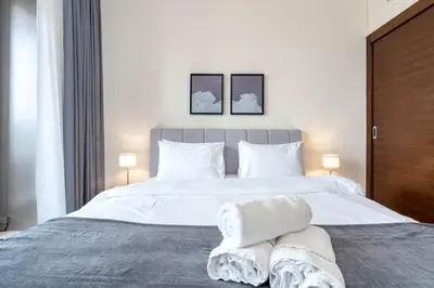 a bedroom with a large white bed with two towels on it at Gala Guests - Deluxe Sparkle Residences Dubai Marina in Dubai