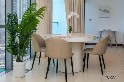 a dining room with a table and chairs and a plant at Skyline & Lake views - Home Cinema - 1-BHK - Prime Location in Dubai