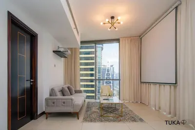 a living room with a couch and a large window at Skyline & Lake views - Home Cinema - 1-BHK - Prime Location in Dubai