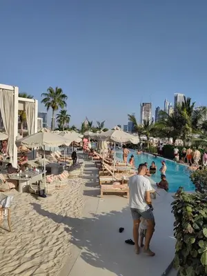 a man standing on the beach next to a swimming pool at 7 palm jumeirah West Beach in Dubai