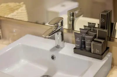 a bathroom sink with a faucet and cups on it at Daniels Poolside Studio in Meydan in Dubai