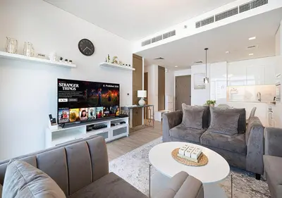a living room with two couches and a tv at Palace Residences 2BR with Stunning Creek Views in Dubai
