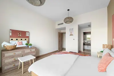 a bedroom with a white bed and a chair at Aesthetic Beach Apartment , Sleeps 6, Pool, Gym & Waterfront Views in Dubai