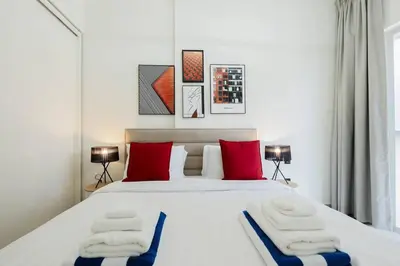 a bedroom with a large bed with red and blue pillows at Luxury at Socio Dubai Hills, 2 Beds, Sleeps 4 - DVH Holiday Homes in Dubai