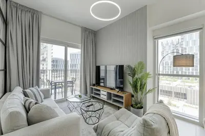 a living room with a white couch and a tv at Luxury at Socio Dubai Hills, 2 Beds, Sleeps 4 - DVH Holiday Homes in Dubai