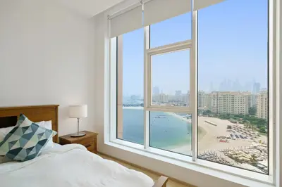 a bedroom with a large window with a view of a beach at Stellar 2BR on Palm Jumeirah - Beach and Pool access in Dubai