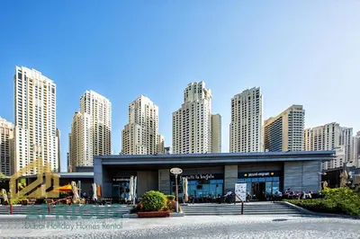 a building in front of a city with tall buildings at Luxury 2Bedroom with Stunning Sea View in JBR in Dubai
