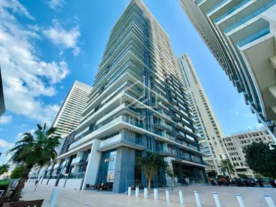 a tall building with palm trees in front of it at Stunning 2 Bedroom in Emaar Beachfront in Dubai